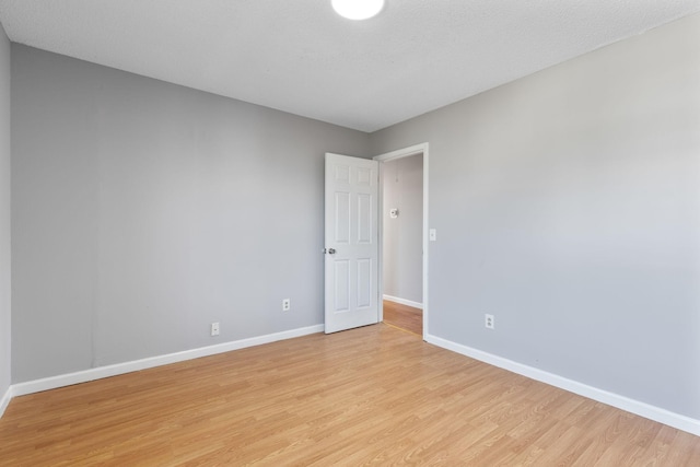 empty room with light hardwood / wood-style floors and a textured ceiling