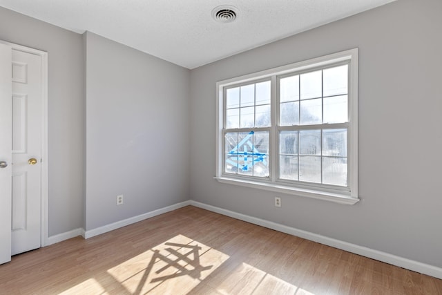 unfurnished room with a textured ceiling and light hardwood / wood-style flooring