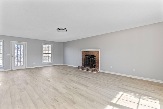 unfurnished living room featuring light hardwood / wood-style floors and a brick fireplace