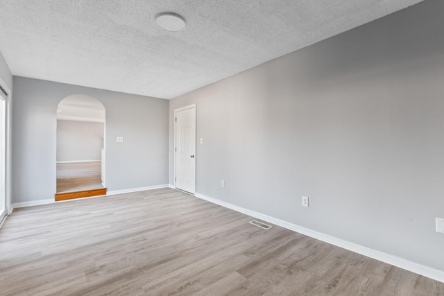 unfurnished room featuring light wood-type flooring and a textured ceiling