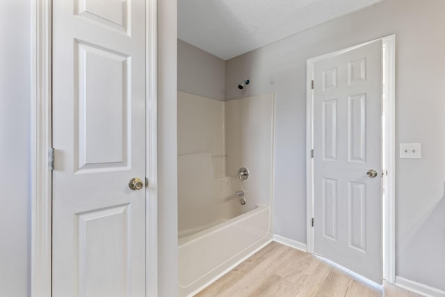 bathroom with  shower combination, a textured ceiling, and wood-type flooring