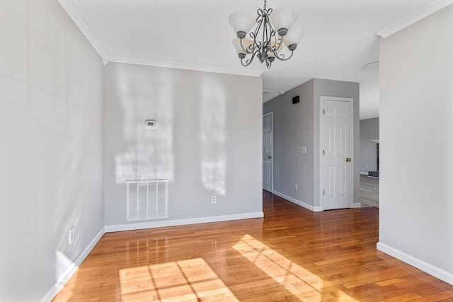 empty room with wood-type flooring, crown molding, and an inviting chandelier