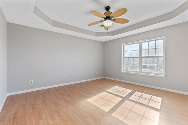 spare room featuring ceiling fan, a raised ceiling, light hardwood / wood-style floors, and a textured ceiling