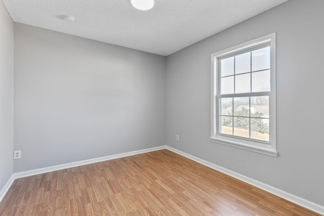 spare room featuring light hardwood / wood-style flooring and a textured ceiling