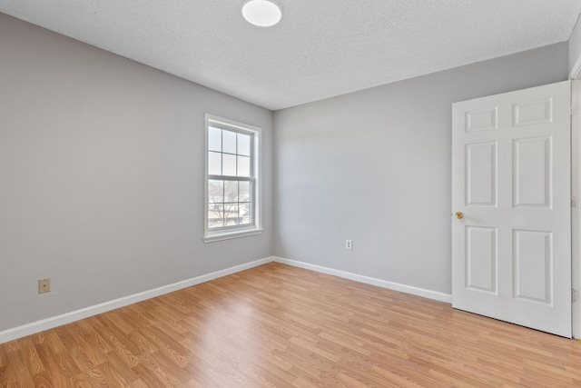 spare room featuring light hardwood / wood-style floors and a textured ceiling