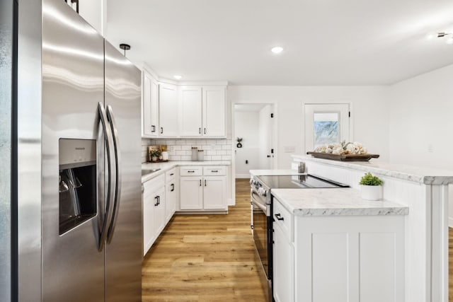 kitchen with white cabinetry, appliances with stainless steel finishes, light hardwood / wood-style flooring, and tasteful backsplash