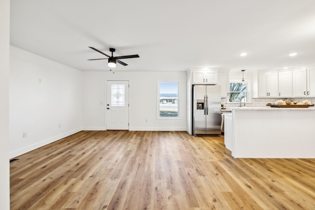 kitchen featuring pendant lighting, white cabinetry, stainless steel fridge, and light hardwood / wood-style flooring