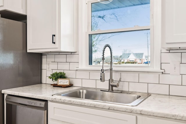 kitchen with white cabinetry, stainless steel appliances, tasteful backsplash, sink, and light stone counters