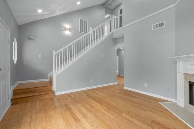 unfurnished living room featuring light hardwood / wood-style floors, high vaulted ceiling, and a fireplace