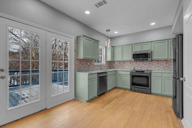 kitchen with appliances with stainless steel finishes, green cabinetry, decorative backsplash, sink, and decorative light fixtures