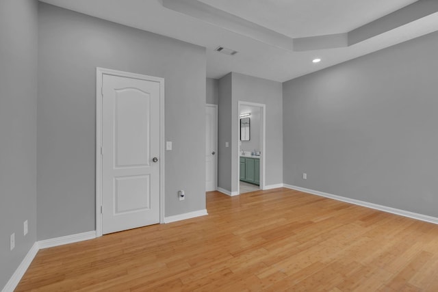 empty room featuring a raised ceiling and light wood-type flooring