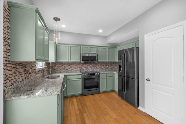 kitchen with sink, green cabinets, appliances with stainless steel finishes, and pendant lighting