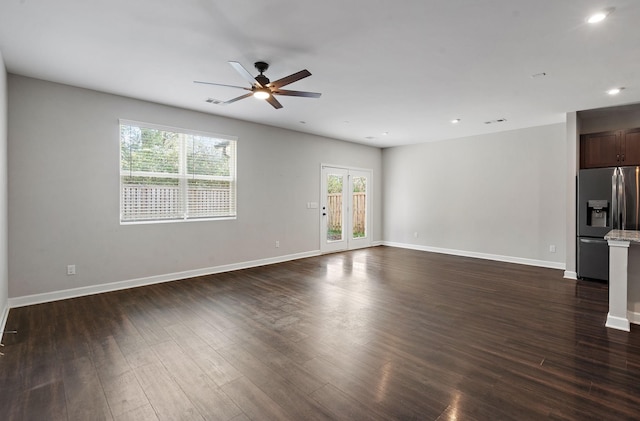 spare room featuring ceiling fan, a healthy amount of sunlight, and dark wood-type flooring