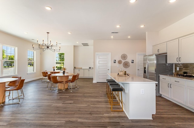 kitchen with white cabinets, a kitchen island, pendant lighting, dark hardwood / wood-style flooring, and a breakfast bar area