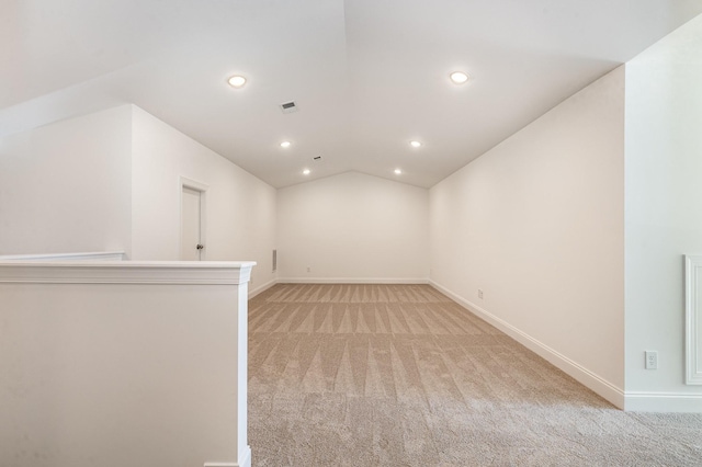 empty room with light colored carpet and vaulted ceiling