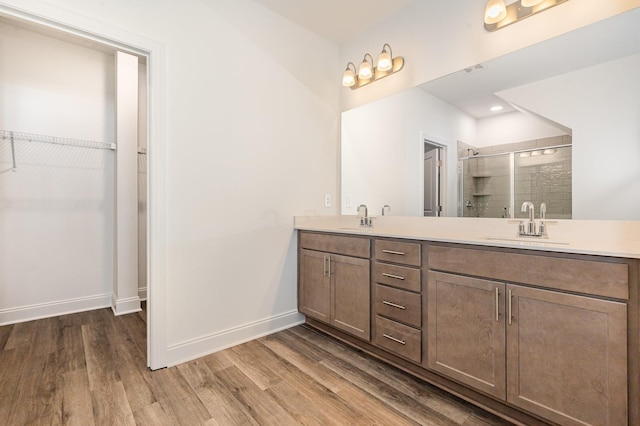 bathroom featuring hardwood / wood-style flooring, a shower with shower door, and vanity