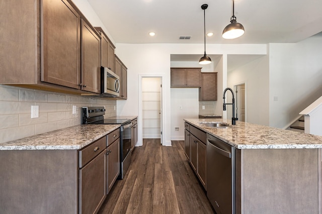 kitchen with pendant lighting, appliances with stainless steel finishes, sink, light stone counters, and dark hardwood / wood-style floors