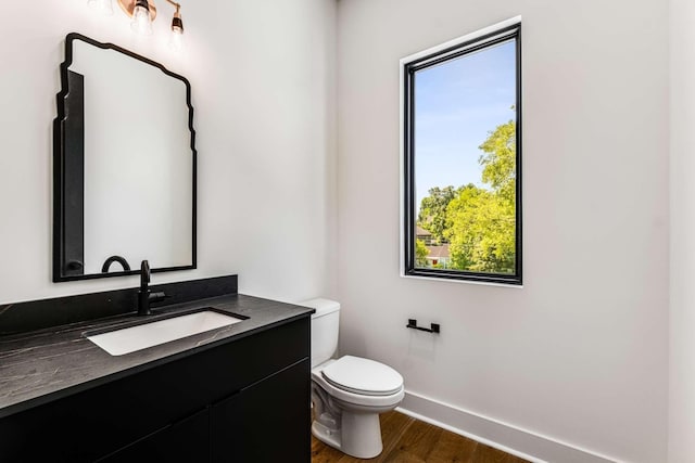 bathroom with toilet, baseboards, wood finished floors, and vanity