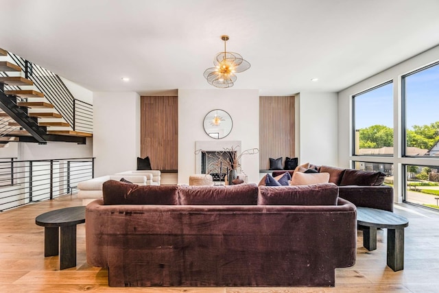 living room featuring light wood finished floors, recessed lighting, a fireplace, and an inviting chandelier