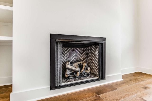 room details featuring a fireplace, baseboards, and wood finished floors