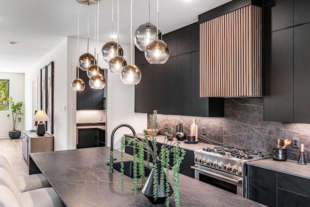 kitchen featuring decorative backsplash, a sink, modern cabinets, dark cabinets, and high end stove