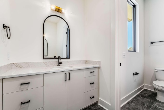 bathroom featuring toilet, baseboards, and vanity