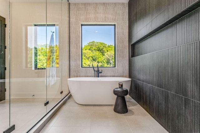 bathroom featuring a stall shower, a soaking tub, tile walls, and tile patterned floors