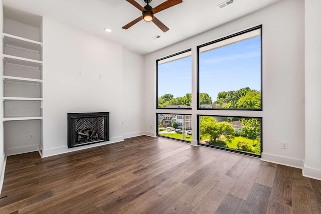 unfurnished living room with dark wood-style flooring, visible vents, a fireplace, and baseboards