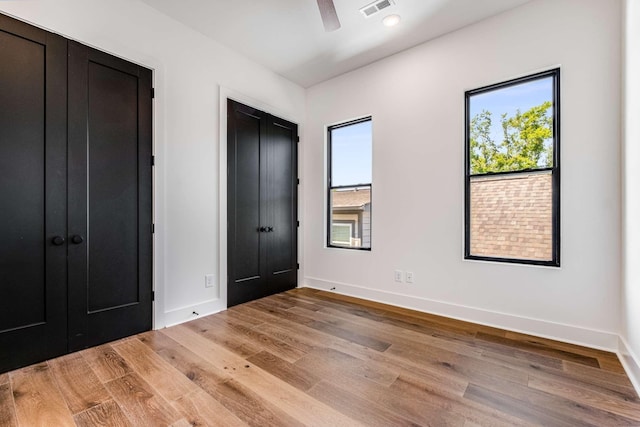 unfurnished bedroom with a ceiling fan, light wood-type flooring, visible vents, and baseboards