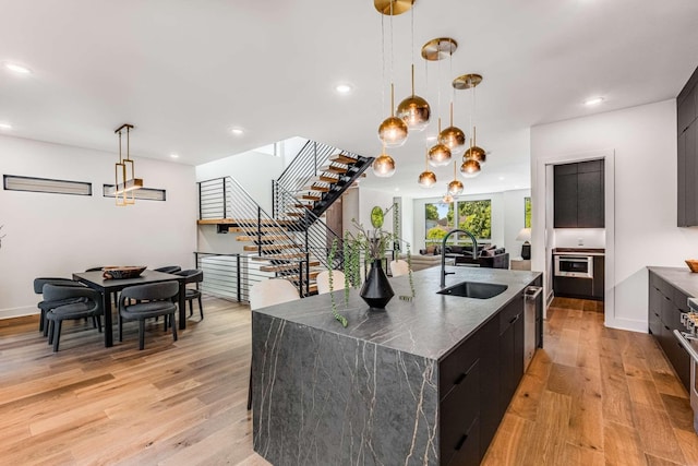 kitchen with pendant lighting, a spacious island, light wood-style flooring, a sink, and modern cabinets