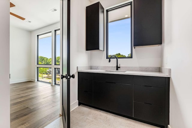 bathroom with visible vents, vanity, baseboards, and wood finished floors