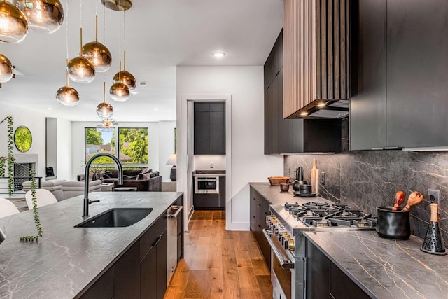 kitchen with a sink, open floor plan, hanging light fixtures, appliances with stainless steel finishes, and modern cabinets