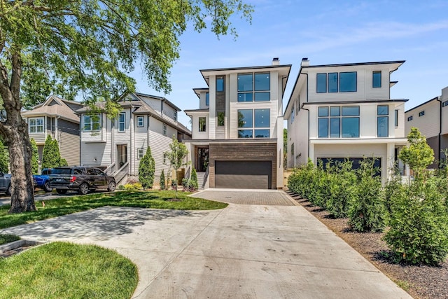 modern home with driveway, a residential view, a chimney, an attached garage, and stucco siding