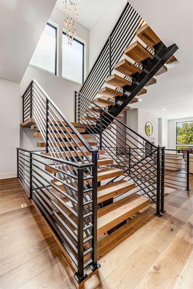 staircase featuring an inviting chandelier, baseboards, and wood finished floors