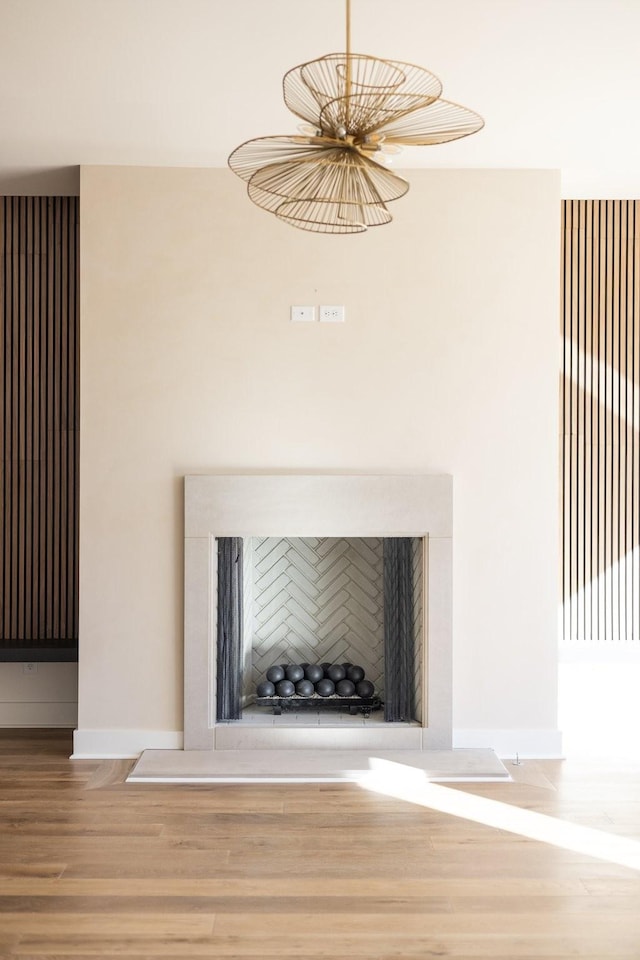 room details featuring a fireplace with raised hearth, baseboards, and wood finished floors