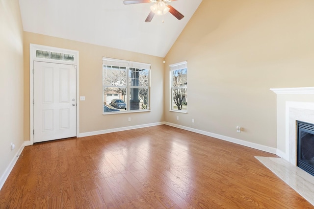 unfurnished living room with ceiling fan, hardwood / wood-style floors, high vaulted ceiling, and a premium fireplace