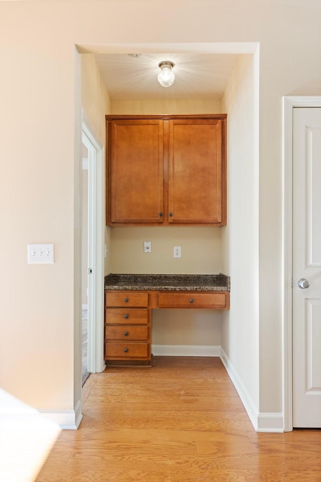 kitchen with built in desk and light hardwood / wood-style floors