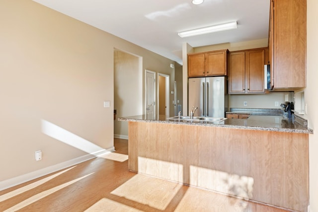 kitchen featuring kitchen peninsula, sink, stone countertops, and high end refrigerator