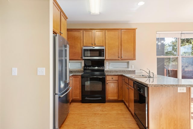 kitchen with black appliances, light wood-type flooring, kitchen peninsula, and sink