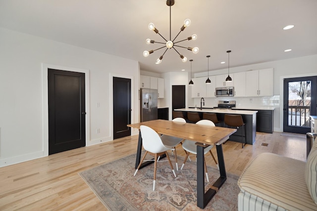 dining room featuring sink, light hardwood / wood-style floors, and an inviting chandelier