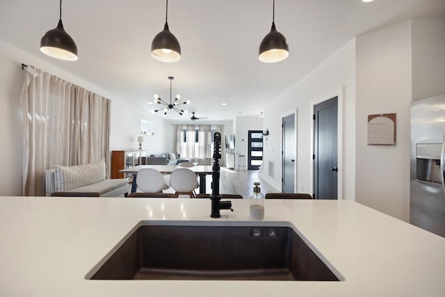 kitchen featuring a notable chandelier, sink, pendant lighting, and stainless steel fridge