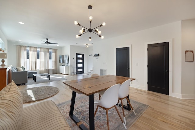 dining space with light hardwood / wood-style floors and ceiling fan with notable chandelier