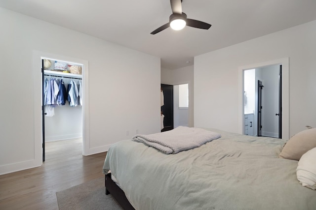 bedroom featuring a spacious closet, hardwood / wood-style floors, connected bathroom, a closet, and ceiling fan