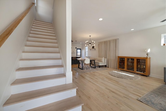 staircase with hardwood / wood-style flooring and an inviting chandelier