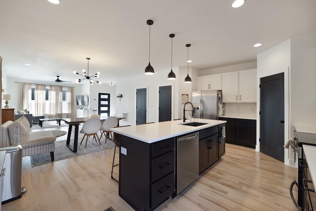 kitchen with pendant lighting, sink, white cabinetry, a center island with sink, and stainless steel appliances