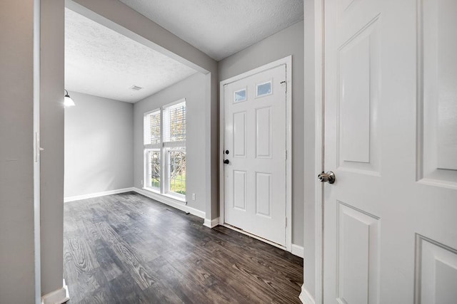 entryway with dark wood-type flooring and a textured ceiling