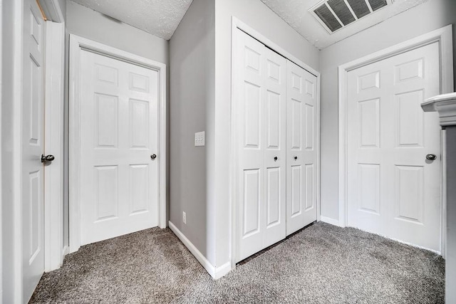 corridor with dark colored carpet and a textured ceiling