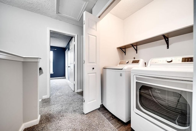 laundry area with a textured ceiling, dark carpet, and washing machine and clothes dryer