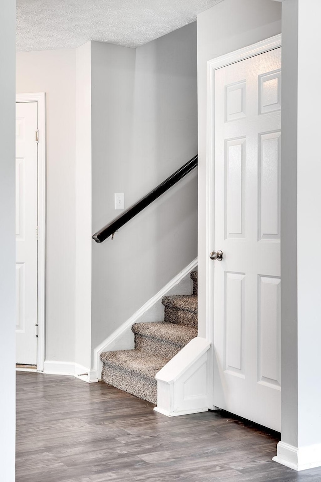 stairs featuring a textured ceiling and wood-type flooring