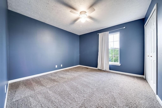 empty room featuring ceiling fan, a textured ceiling, and carpet